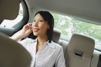Businesswoman in backseat of car using mobile phone - Asia Images Group
