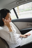 Businesswoman in car on the phone and using laptop - Asia Images Group