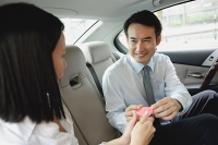 Businessman and businesswoman in backseat of car, exchanging business cards - Asia Images Group
