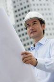 Man in hardhat, holding blueprints - Asia Images Group