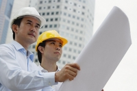 Two businessmen with blueprints, buildings in the background - Asia Images Group