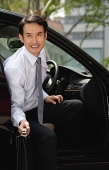 Businessman getting out of car, smiling - Asia Images Group