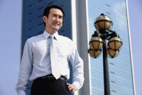 Businessman standing with hand on hip, looking away - Asia Images Group