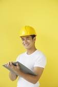 Man wearing hardhat, holding clipboard - Asia Images Group