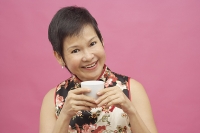 Mature woman holding Chinese tea cup - Asia Images Group