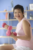 Mature woman using dumbbells at home - Asia Images Group