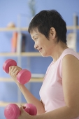 Mature woman using dumbbells - Asia Images Group