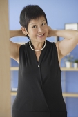 Mature woman putting on pearl necklace - Asia Images Group