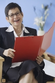 Businesswoman holding clipboard, smiling - Asia Images Group