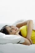 Young woman lying on bed, embracing pillow - Asia Images Group