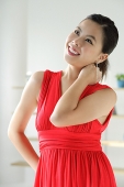 Young woman in red dress, hand on neck, looking up - Asia Images Group