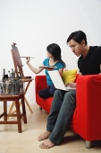 Woman painting on easel, man using laptop - Asia Images Group