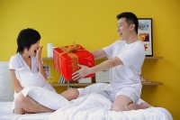 Man giving woman present in bedroom - Asia Images Group