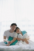Couple sitting on bed, eyes closed - Asia Images Group