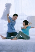 Couple in bedroom having a pillow fight - Asia Images Group