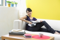 Woman sitting on sofa, looking at camera - Asia Images Group