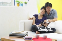 Couple in living room, looking at magazine - Asia Images Group