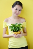 Woman holding house plant - Asia Images Group