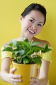 Woman holding house plant, smiling - Asia Images Group
