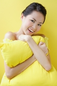 Woman embracing pillow, smiling at camera - Asia Images Group