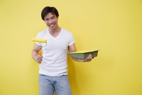 Man holding paint roller and paint tray - Asia Images Group