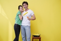 Couple standing together, man holding paint roller - Asia Images Group