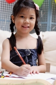 Young girl with pencil and paper, smiling at camera - Asia Images Group