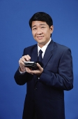 Businessman standing, holding calculator - Asia Images Group