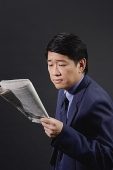 Businessman reading newspaper, studio shot - Asia Images Group