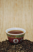 Chinese teacup and pile of loose tea leaves, still life - Asia Images Group