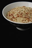 Bowl of uncooked rice against black background - Asia Images Group