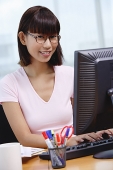 Young woman sitting in front of computer, smiling at camera - Asia Images Group