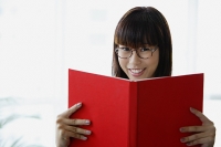 Young woman holding book, smiling at camera - Asia Images Group