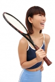 Young woman holding tennis racket over shoulder, smiling - Asia Images Group