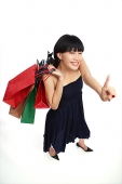 Young woman carrying shopping bags, pointing finger - Asia Images Group