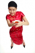 Young woman in cheongsam holding cup of tea - Asia Images Group