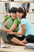 Young women listening to MP3 player, smiling at camera - Asia Images Group