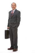 Businessman standing with briefcase, portrait - Asia Images Group