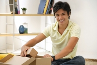 Man sitting with box, smiling at camera - Asia Images Group