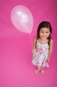 Girl holding balloon, smiling at camera - Asia Images Group