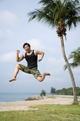 Man jumping in air, looking at camera - Asia Images Group