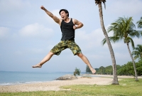 Man jumping in air, arms outstretched - Asia Images Group