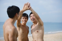 Three men on beach, putting hands together - Asia Images Group