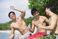 Three men sitting side by side, holding bottle of water - Asia Images Group