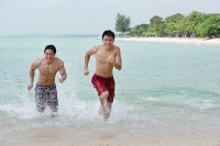 Two men running along the beach - Asia Images Group