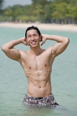 Man standing in sea, hands on head - Asia Images Group