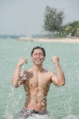 Man standing in sea, splashing water - Asia Images Group