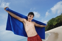 Man standing on beach, holding towel - Asia Images Group