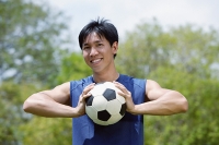 Man holding soccer ball in both hands - Asia Images Group