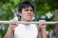 Young man doing chin-ups, clenching teeth - Asia Images Group